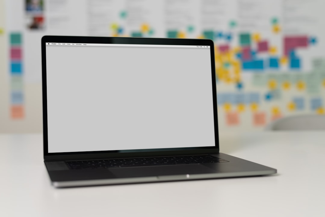 A laptop on a white desk with an empty screen and blurred background.
