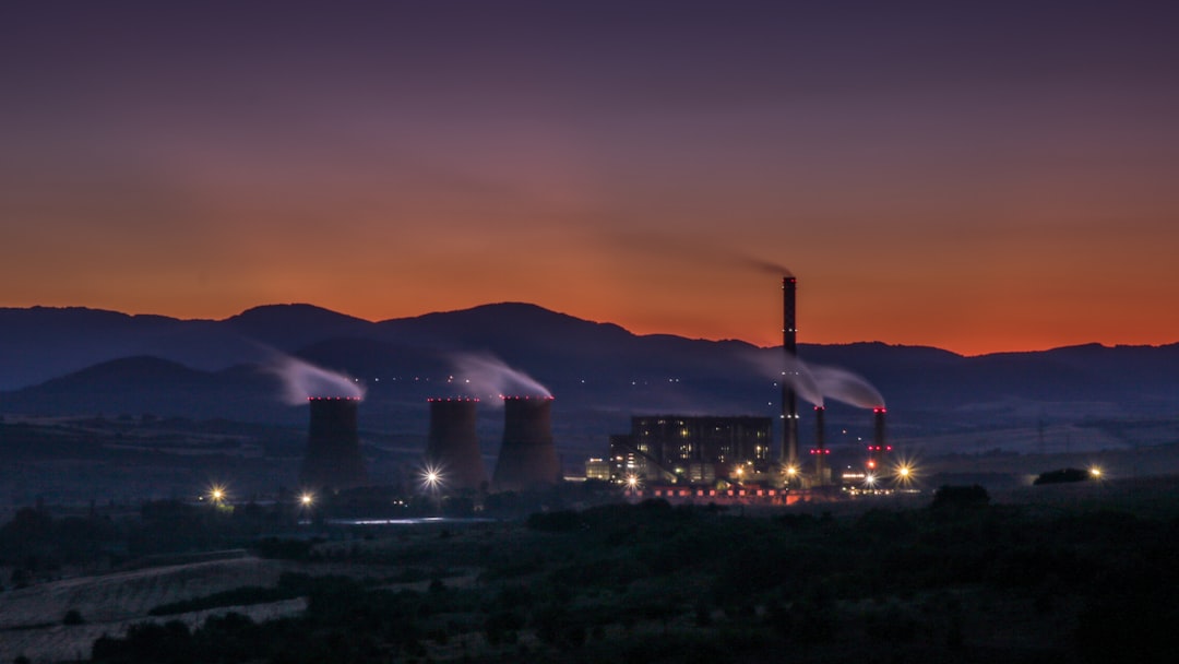 Thermal power plant against a sunset skyline with smoke billowing from cooling towers
